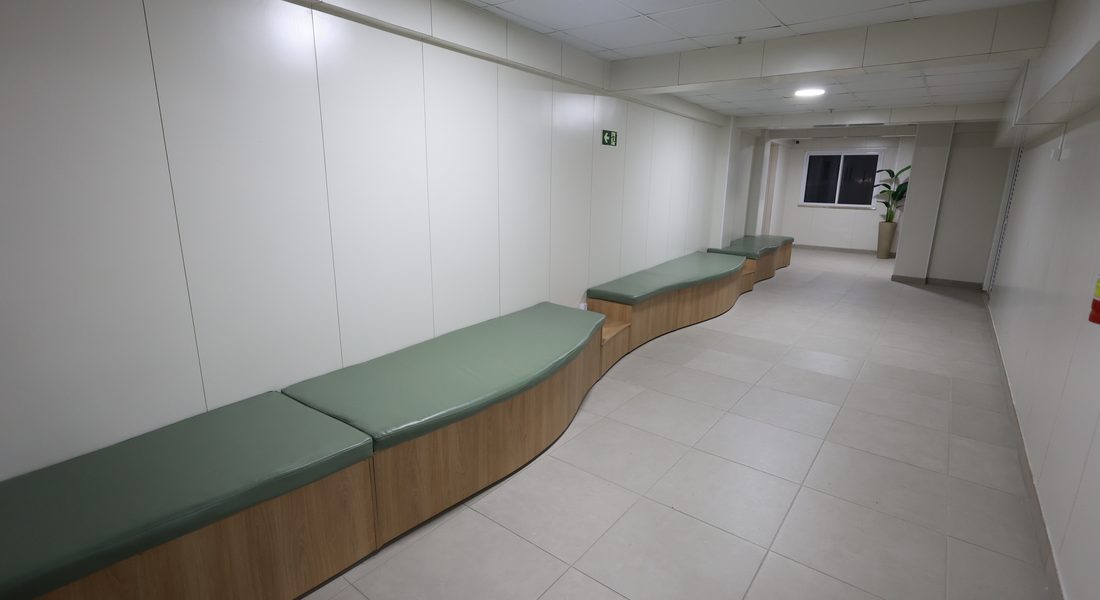 Corredor da clínica com banco corrido acolchoado, piso nivelado e circulação livre